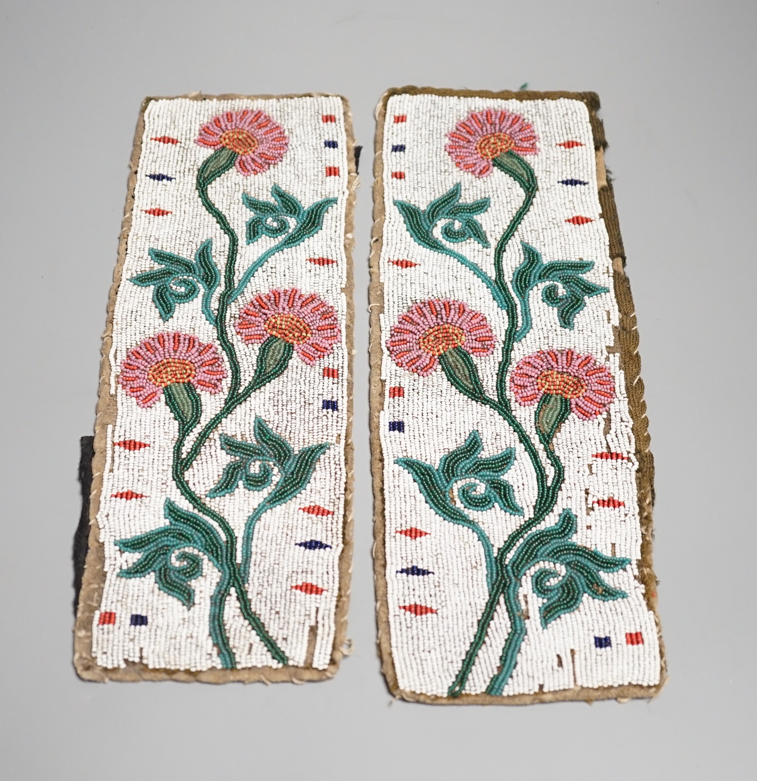 A fine pair of Native American Plains Indian rectangular beadwork panels, with floral designs and tribal markings, leather backing with remains of fabric edges, length 30cms